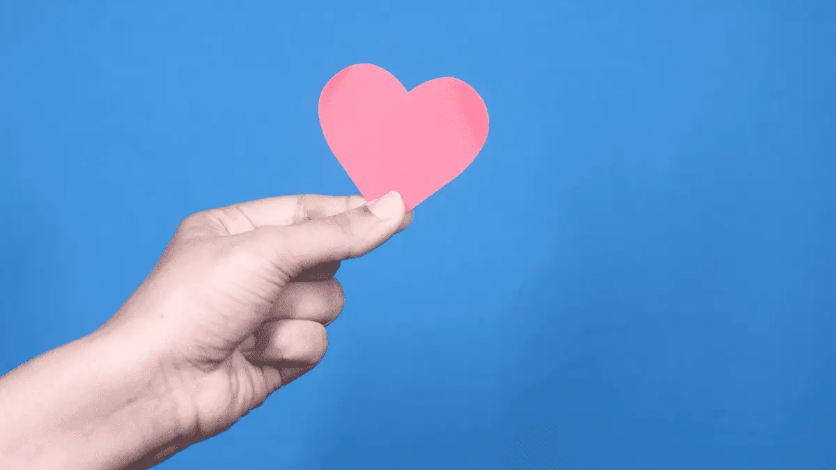 A Hand Holding Red Heart with Copy Space against Blue Background