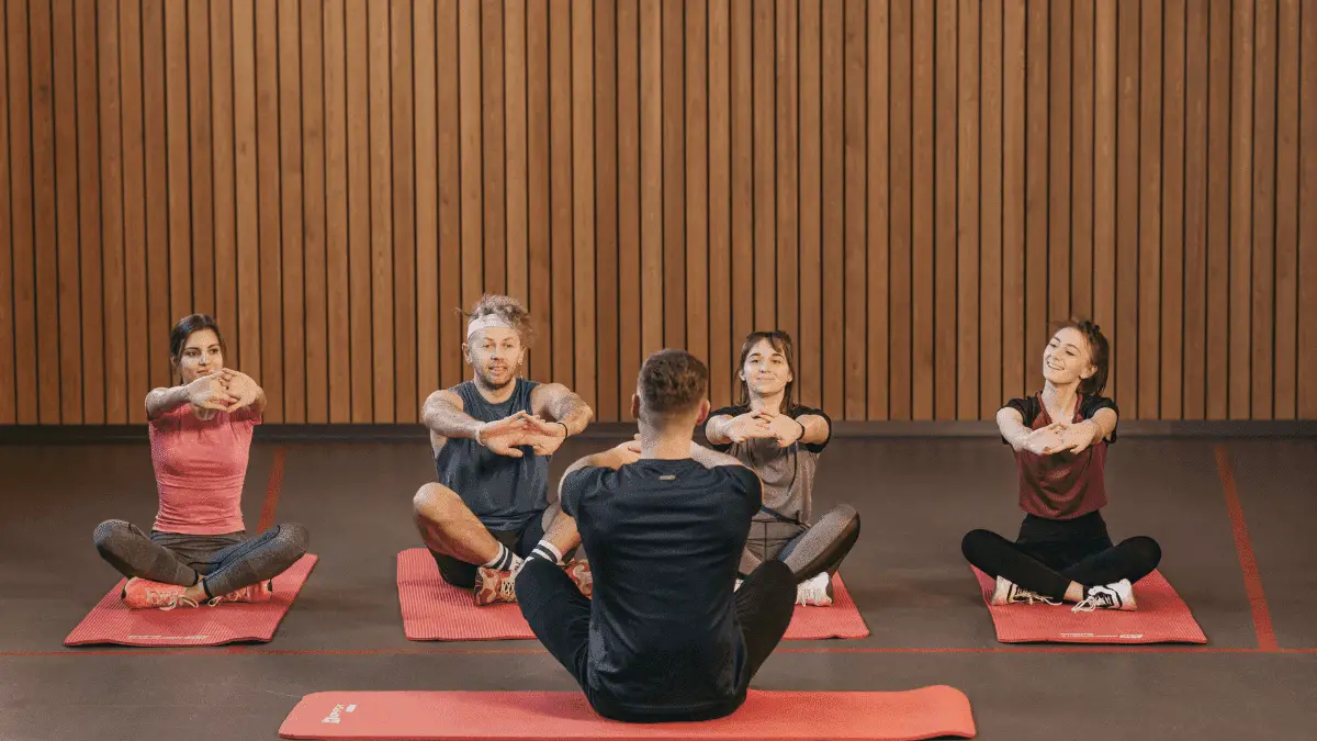 3 Men and 2 Women sitting on Red Yoga Mat