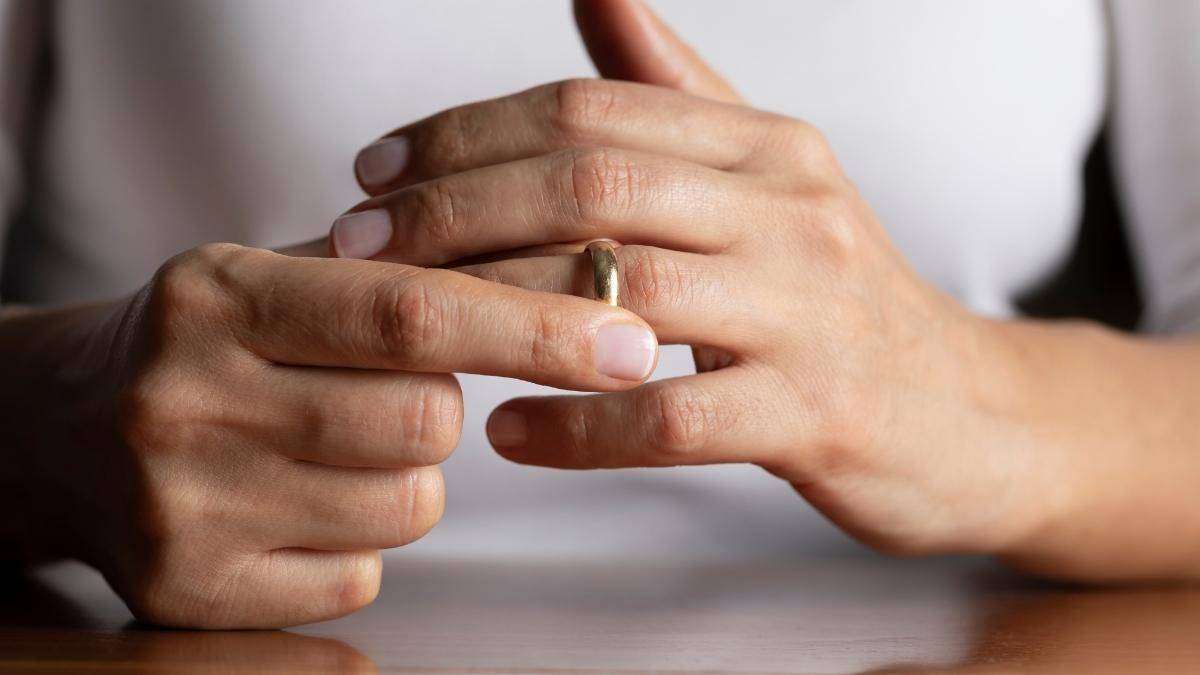 A woman removing her wedding ring to show signs you need a divorce