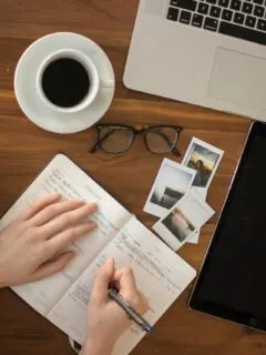 person holding ballpoint pen writing on notebook