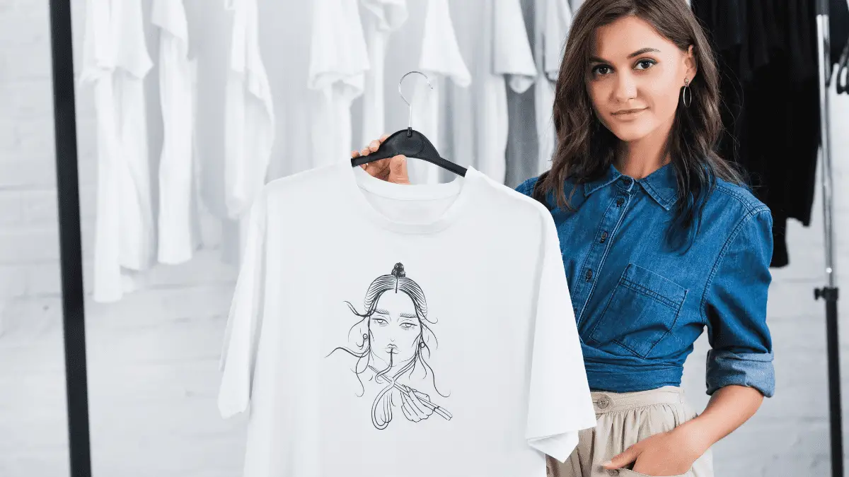 A woman holding a white T-shirt she designed